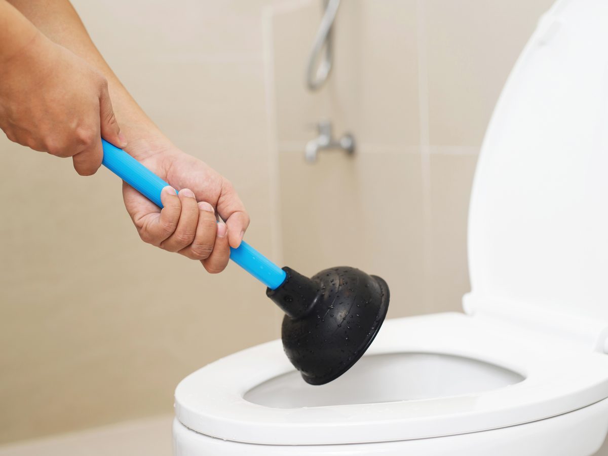 Hand plunger being worked in a blocked toilet pan